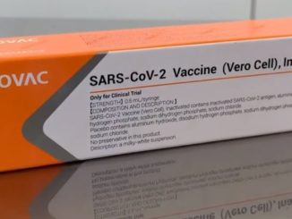 Caixa contendo a vacina do covid-19. Sobre um fundo laranja, lê-se "Sinovac", que é a empresa da vacina.